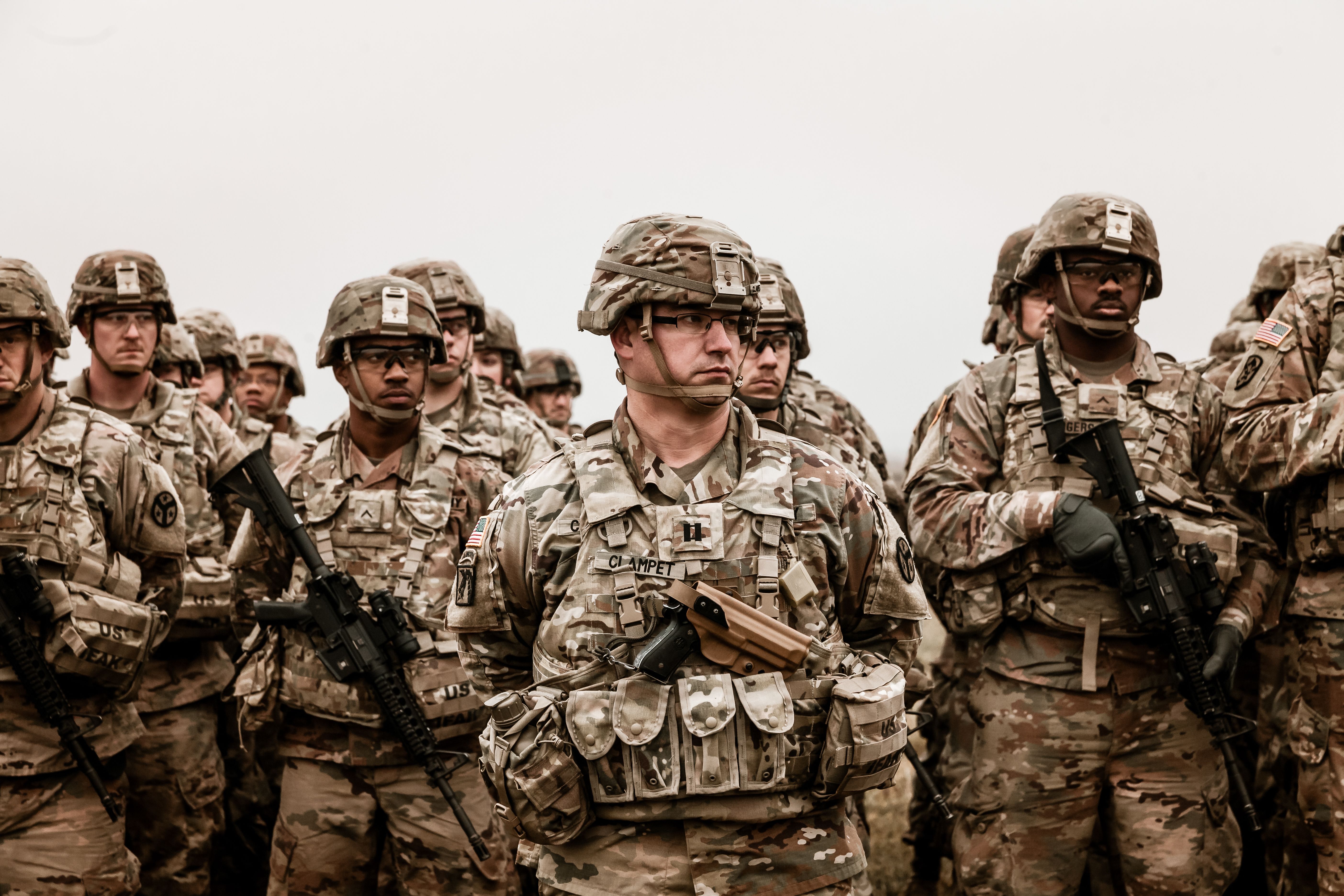 A group of soldiers in camouflage uniforms standing outdoors and holding rifles.